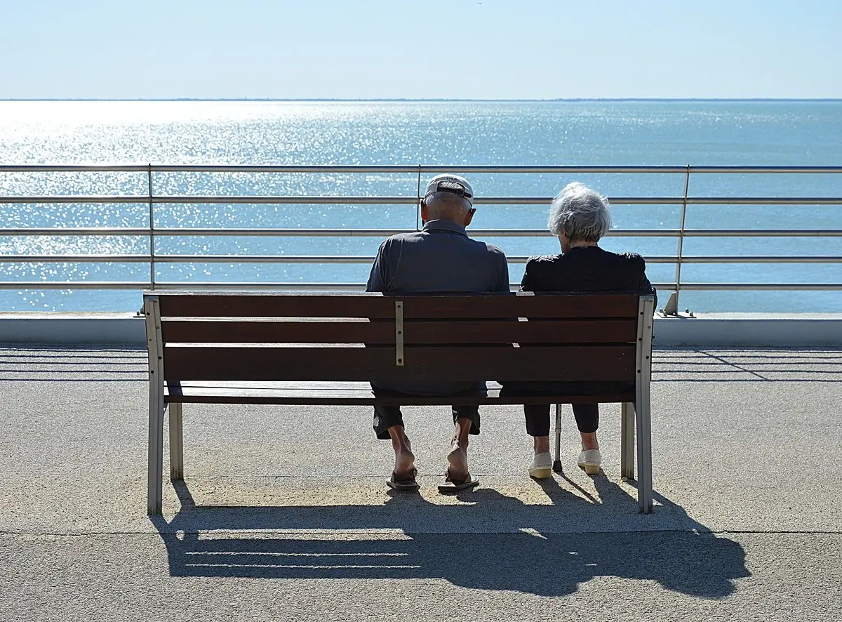 People sitting on bench with ocean in background
