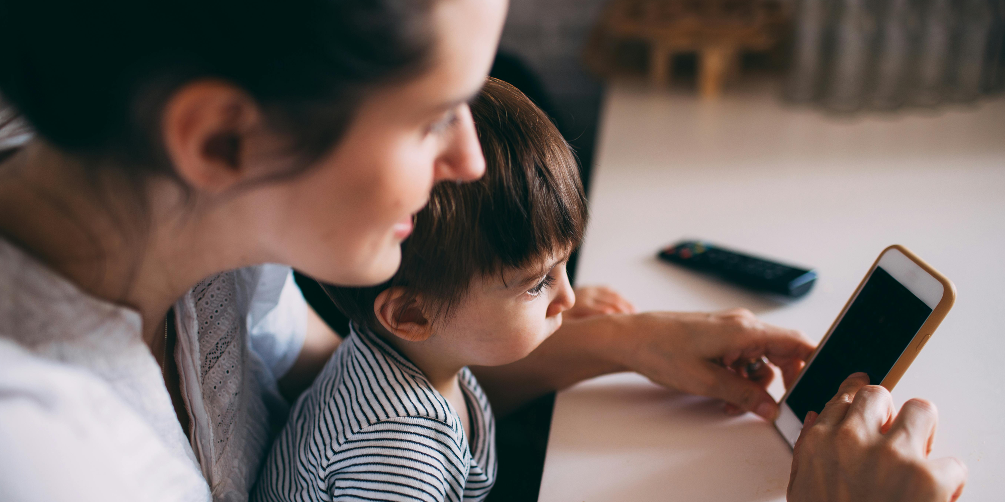 A woman holding her baby and her phone